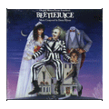 Beetlejuice cover featuring the ghost with the most sitting atop the house in the middle of the two main characters