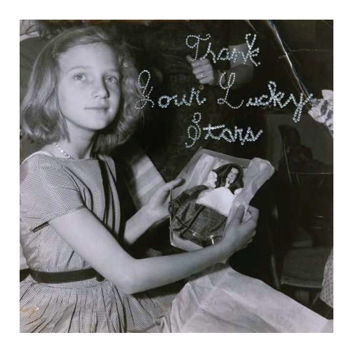 Black and white photo of a girl holding a book titled 'Thank Your Lucky Stars'. beach house