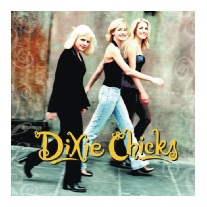 Album cover for Dixie Chicks, featuring the three band members walking side by side against a textured gray wall, with the band's name in large yellow script at the bottom.