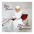 Dolly Parton's 'Home For Christmas' album cover artwork, featuring Dolly Parton in a white fur coat and Santa hat sitting in a white sleigh with a red cushioned seat against a snowy background.
