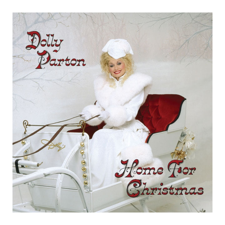 Dolly Parton's 'Home For Christmas' album cover artwork, featuring Dolly Parton in a white fur coat and Santa hat sitting in a white sleigh with a red cushioned seat against a snowy background.