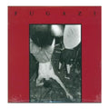 Fugazi album cover featuring a bold red border with the band name in black letters at the top and a black-and-white photo of a live performance in the center.