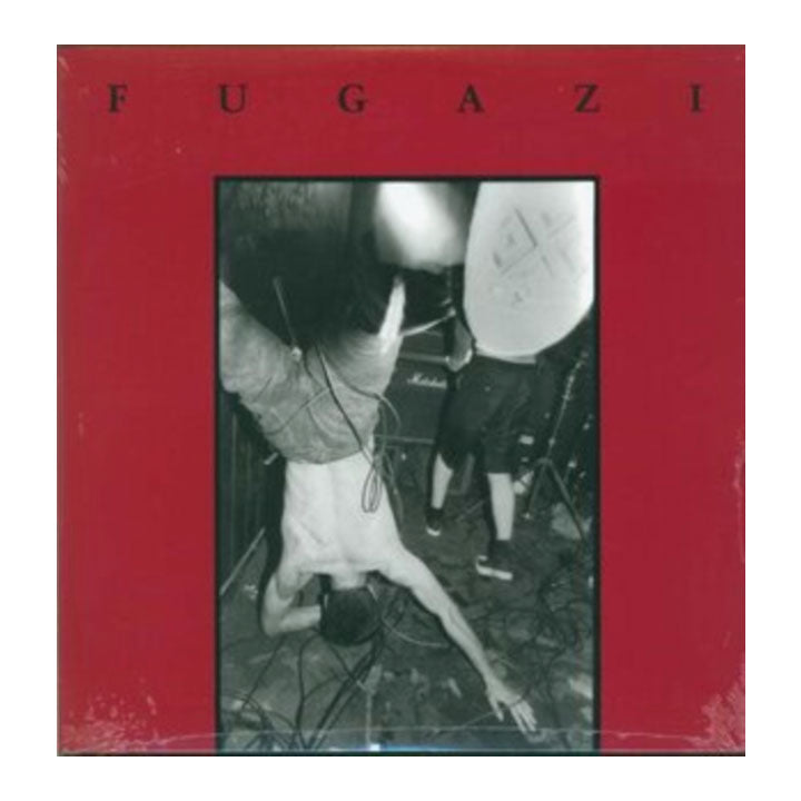 Fugazi album cover featuring a bold red border with the band name in black letters at the top and a black-and-white photo of a live performance in the center.