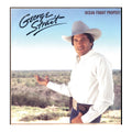Album cover for George Strait's 'Ocean Front Property' featuring the artist in a white cowboy hat and white shirt standing outdoors against a blue sky and desert landscape.