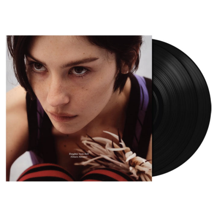 A black vinyl record partially pulled from its album jacket, showing a close-up portrait of a woman with short dark hair and a purple top. Small text on the cover reads 'Doublet for Her' and '(Photo Viewing)'.