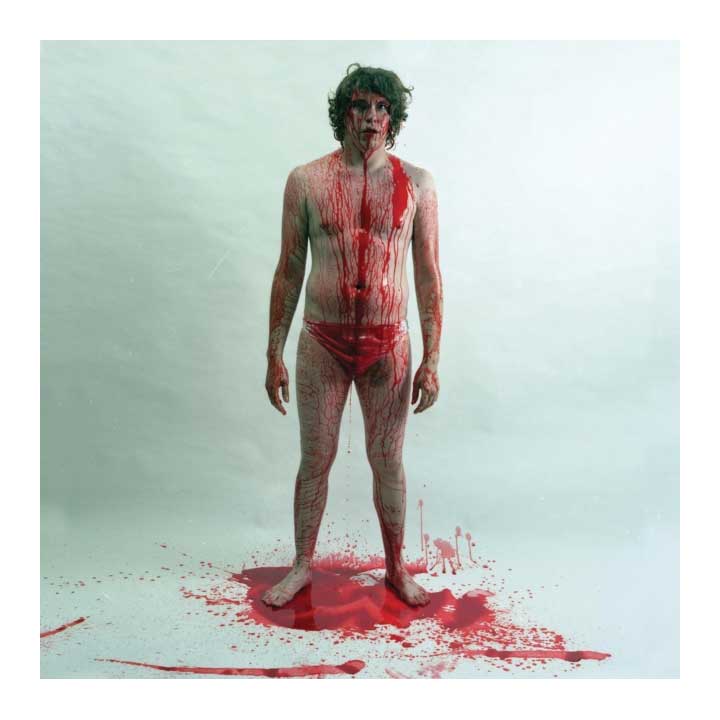 Person with red liquid on body against a light gray background