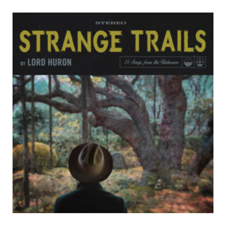 Album cover for 'Strange Trails' by Lord Huron, featuring a black header with yellow title text and a forest scene below showing a figure from behind wearing a hat.