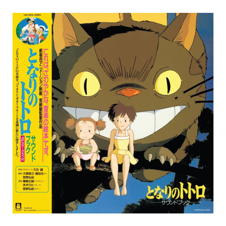 Japanese cover for 'My Neighbor Totoro' (となりのトトロ), featuring the large brown Totoro character, two children sitting on its back, and a bright yellow spine band with Japanese text. 