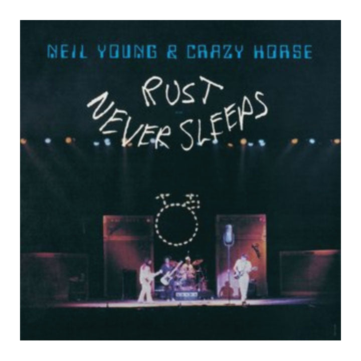 Album cover for Neil Young & Crazy Horse's 'Rust Never Sleeps', featuring a dark concert stage scene with band members performing under spotlights and large white handwritten text across the center.
