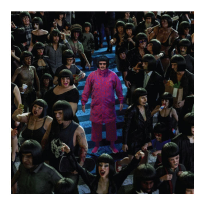 man in pink clothe surrounded by people in drab clothing