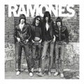 Black and white photo of the Ramones band posing against a graffiti-covered wall.