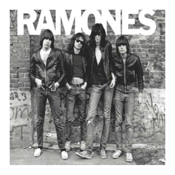 Black and white photo of the Ramones band posing against a graffiti-covered wall.