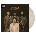 '12-inch vinyl record with a sepia-toned group portrait on the cover and a translucent off-white record partially visible behind it.