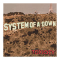 Album cover art for System of A Down's 'Toxicity', featuring the band's name in large cream letters across a dry, brown hillside with industrial structures in the background under a muted sky.