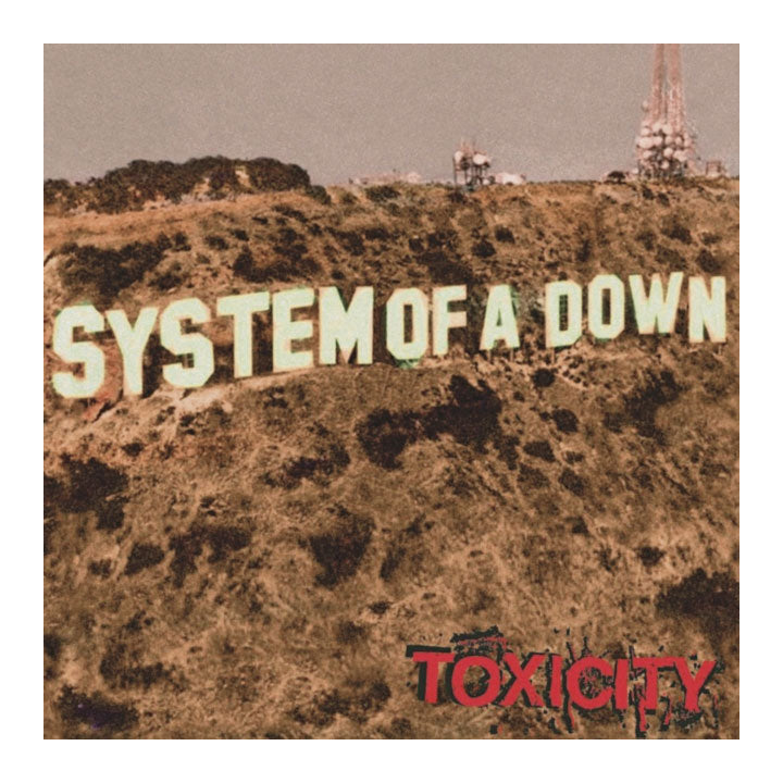 Album cover art for System of A Down's 'Toxicity', featuring the band's name in large cream letters across a dry, brown hillside with industrial structures in the background under a muted sky.