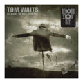 Album cover for Tom Waits' 'Get Behind the Mule (Spiritual)' with a person on a stick against a cloudy sky.