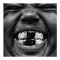 Close-up of a person's mouth with a black object in it, in black and white.